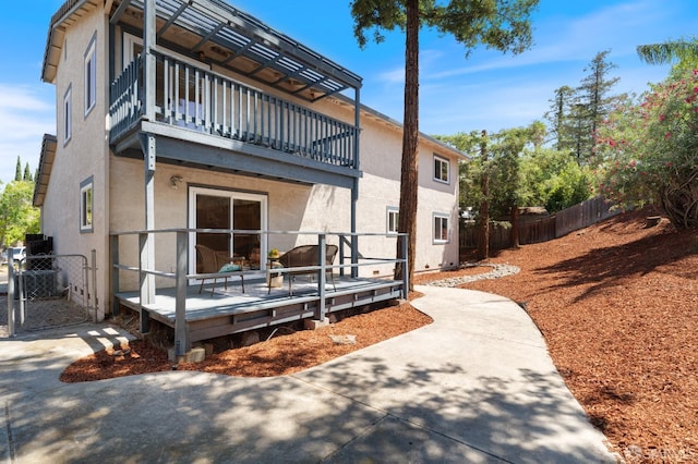 back of house with a balcony and a wooden deck