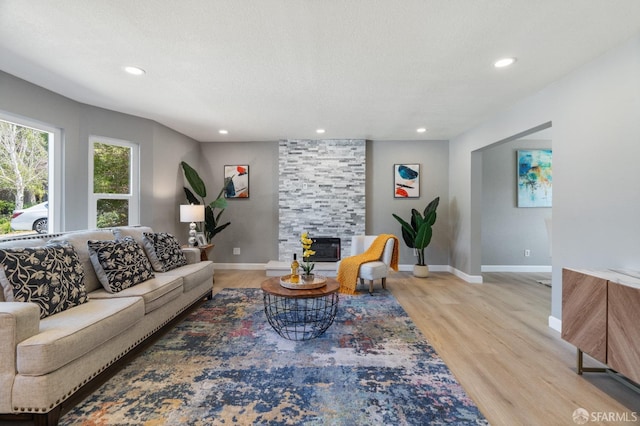 living room with a textured ceiling, light hardwood / wood-style floors, and a fireplace