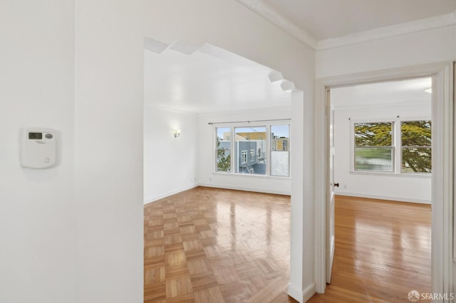 unfurnished room featuring a wealth of natural light, crown molding, and baseboards