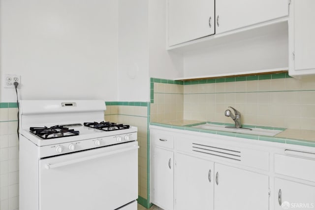 kitchen featuring white gas range oven, white cabinets, and light countertops