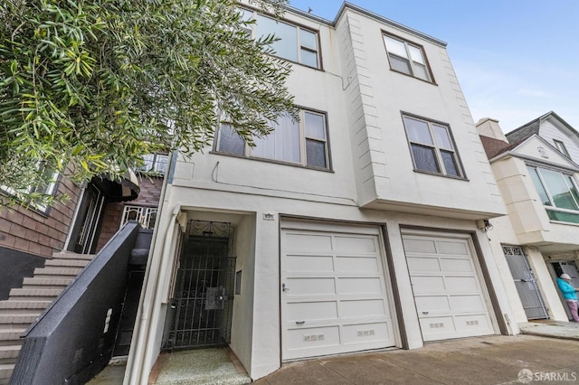 view of property featuring driveway, an attached garage, and stucco siding