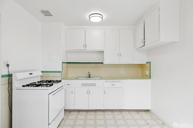 kitchen featuring light floors, light countertops, white cabinetry, a sink, and white range with gas stovetop