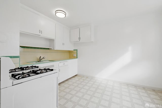 kitchen with white range with gas stovetop, white cabinetry, a sink, and light floors