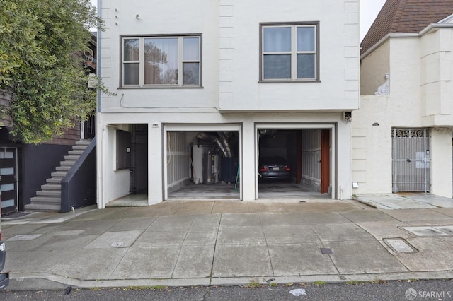 view of front facade featuring driveway, a garage, stairs, and stucco siding