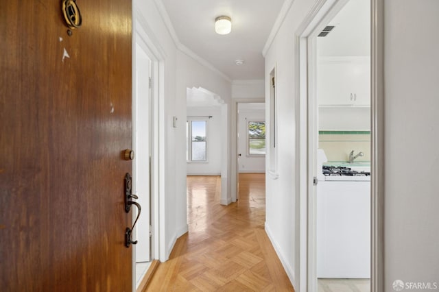 corridor featuring baseboards, arched walkways, and crown molding