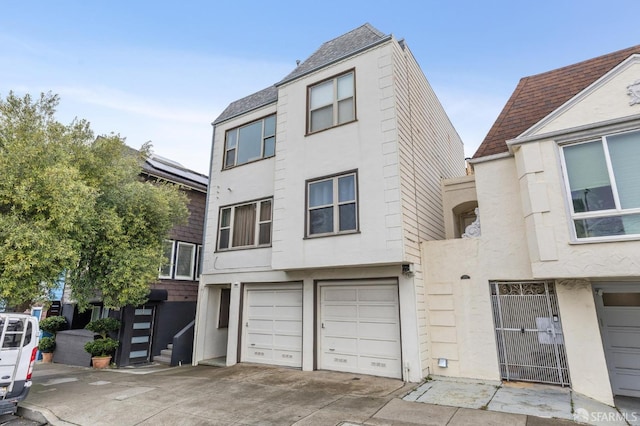 view of property with driveway, an attached garage, and stucco siding