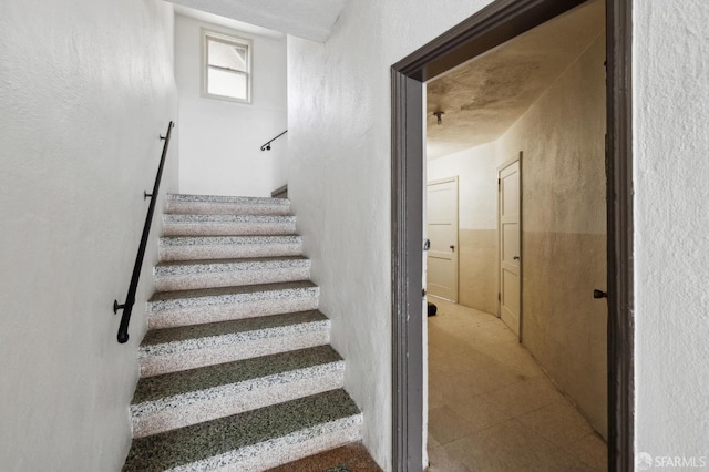 stairway featuring a textured wall and tile patterned floors