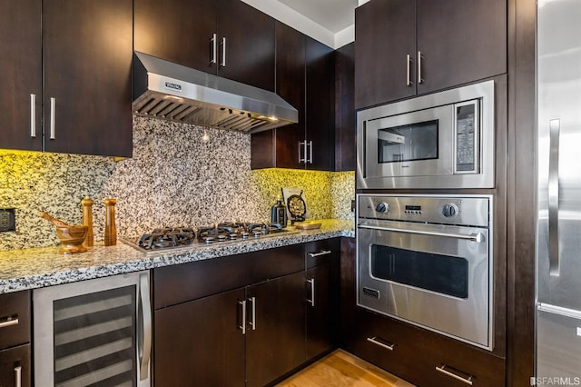 kitchen with tasteful backsplash, light stone countertops, light wood-type flooring, stainless steel appliances, and wine cooler