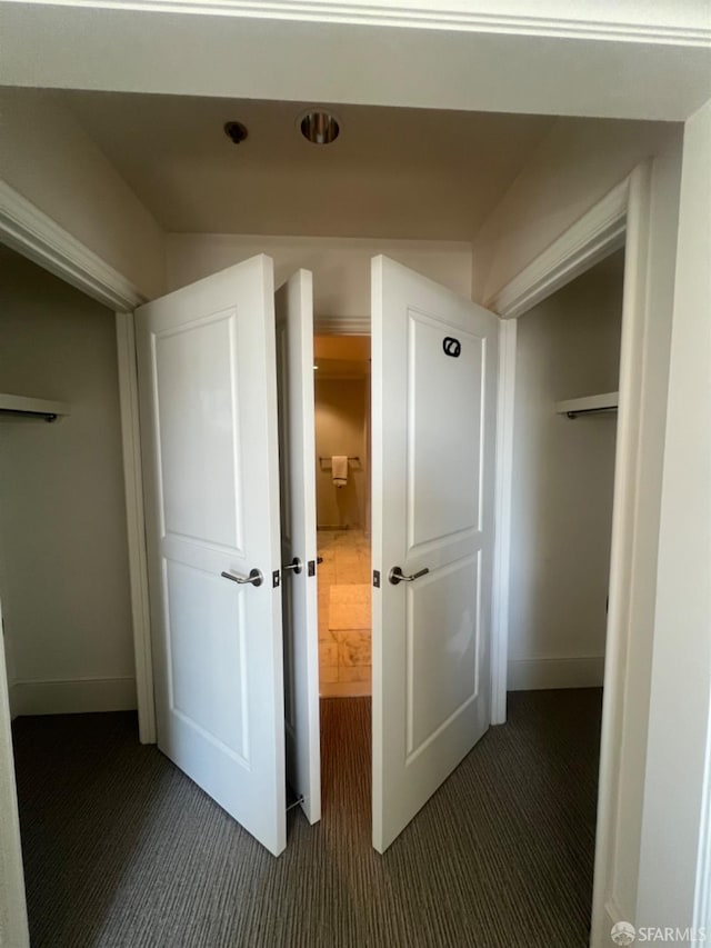 hall with dark colored carpet