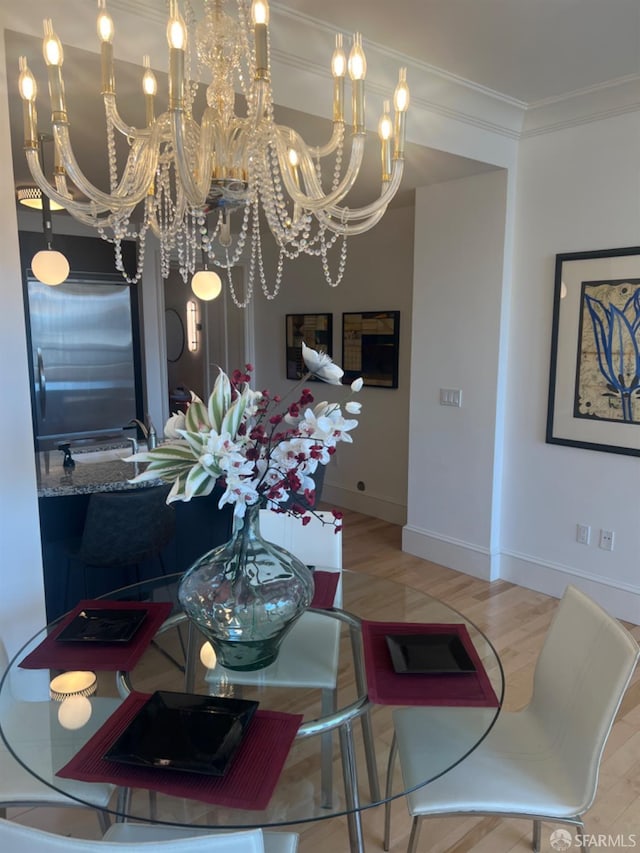 dining space with hardwood / wood-style flooring, ornamental molding, and a chandelier