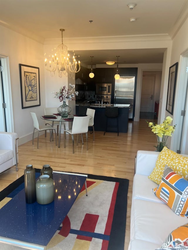 living room with an inviting chandelier, ornamental molding, and wood-type flooring