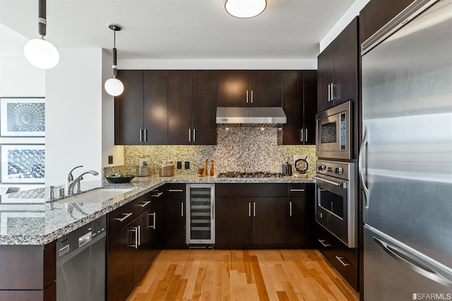 kitchen featuring built in appliances, hanging light fixtures, light hardwood / wood-style flooring, wine cooler, and sink