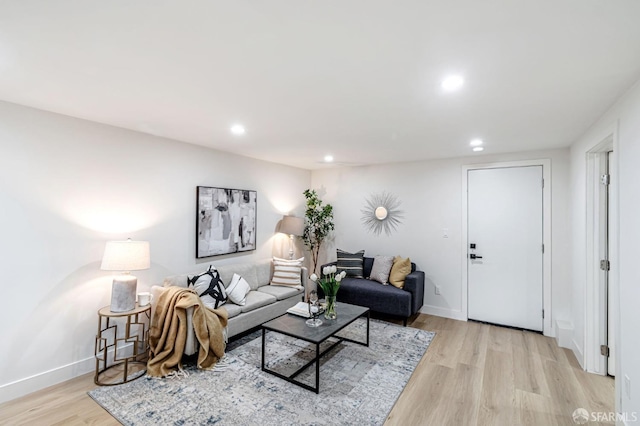 living room with recessed lighting, baseboards, and light wood-type flooring