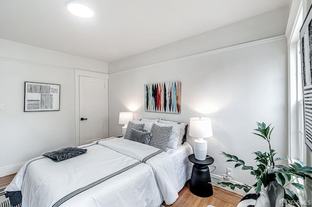 bedroom featuring baseboards, a wall unit AC, and wood finished floors