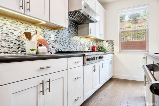 kitchen with ventilation hood, light wood-type flooring, decorative backsplash, white cabinets, and stainless steel gas cooktop