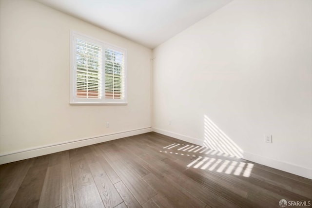 empty room featuring dark wood-type flooring and lofted ceiling