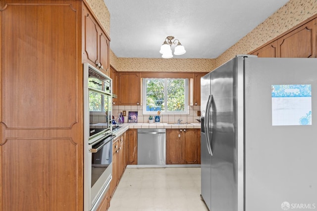 532 Vista Ct, Millbrae, CA 94030 - kitchen featuring appliances with stainless steel finishes, wallpapered walls, light floors, tile countertops, and brown cabinets