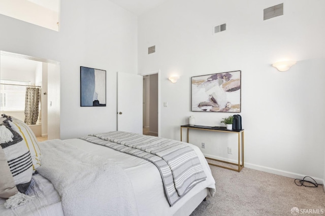 carpeted bedroom featuring a towering ceiling and connected bathroom