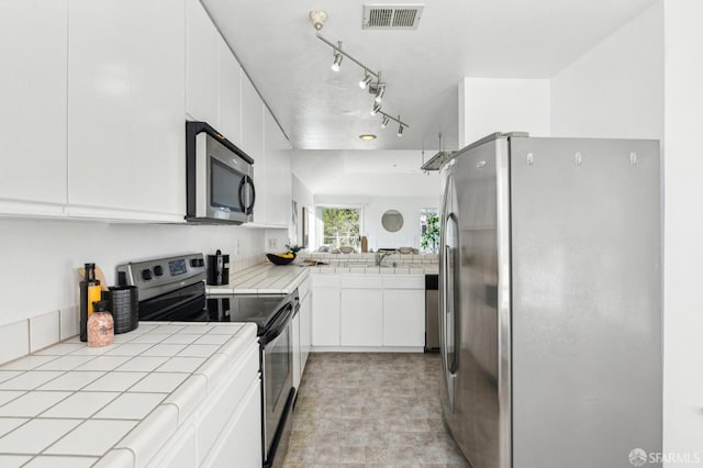 kitchen featuring stainless steel appliances, tile countertops, and white cabinetry