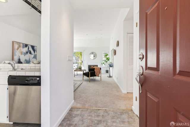 carpeted foyer entrance featuring a tiled fireplace and sink