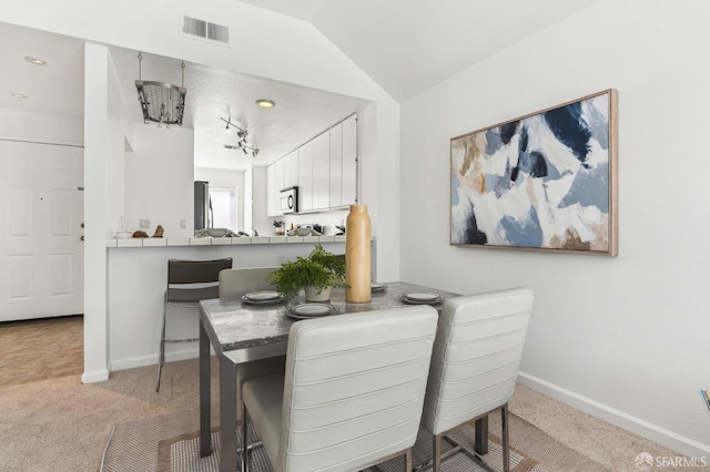 carpeted dining area featuring vaulted ceiling