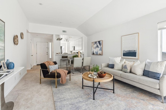 living room featuring lofted ceiling, an inviting chandelier, and light carpet