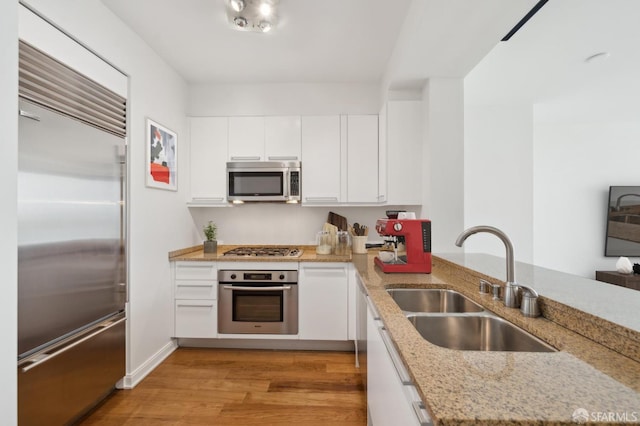 425 1st St Unit 3401, San Francisco, CA 94107 - kitchen featuring stainless steel appliances, a sink, white cabinets, light wood-type flooring, and light stone countertops