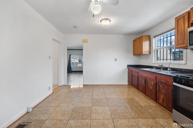 kitchen with appliances with stainless steel finishes, a sink, baseboards, and dark countertops