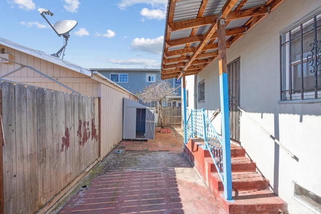 view of patio with a shed, a fenced backyard, and an outdoor structure