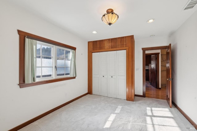 unfurnished bedroom with light colored carpet and a closet