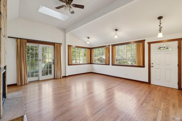 unfurnished living room with hardwood / wood-style floors, plenty of natural light, lofted ceiling with skylight, and ceiling fan