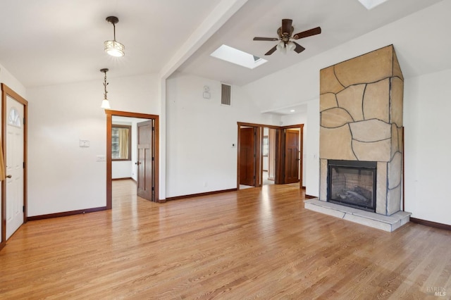 unfurnished living room featuring a fireplace, lofted ceiling with skylight, and light wood-type flooring