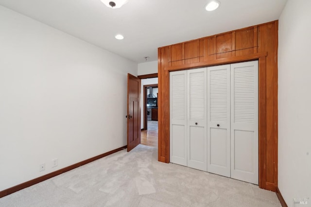 unfurnished bedroom with light colored carpet and a closet