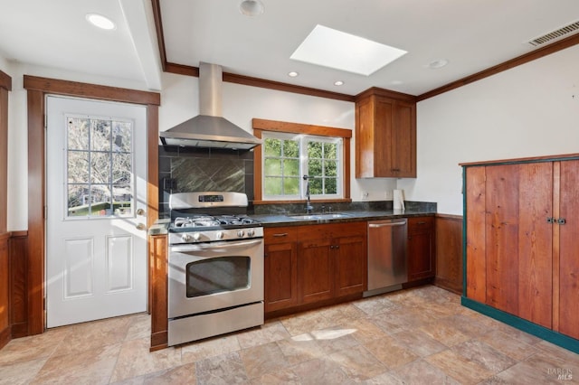 kitchen featuring sink, a skylight, appliances with stainless steel finishes, plenty of natural light, and range hood