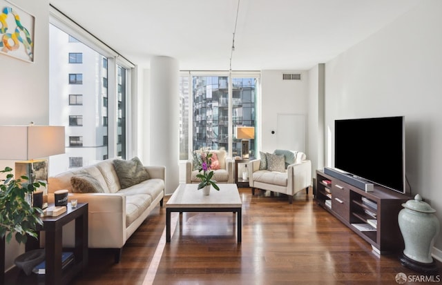 living area featuring dark wood-type flooring, floor to ceiling windows, and visible vents