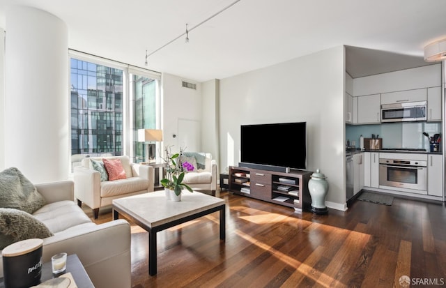 living area featuring rail lighting, visible vents, a wall of windows, and dark wood-style flooring