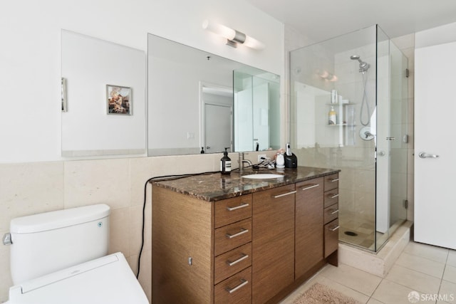 bathroom featuring toilet, tile walls, vanity, tile patterned floors, and a stall shower