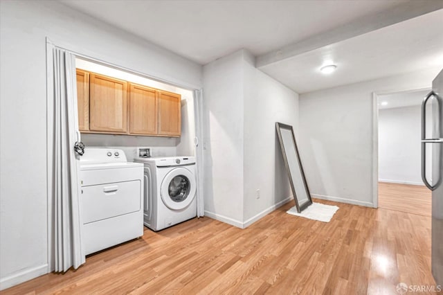 clothes washing area featuring cabinets, washer and dryer, and light wood-type flooring