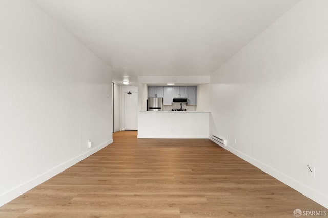 unfurnished living room featuring a baseboard radiator and light wood-type flooring