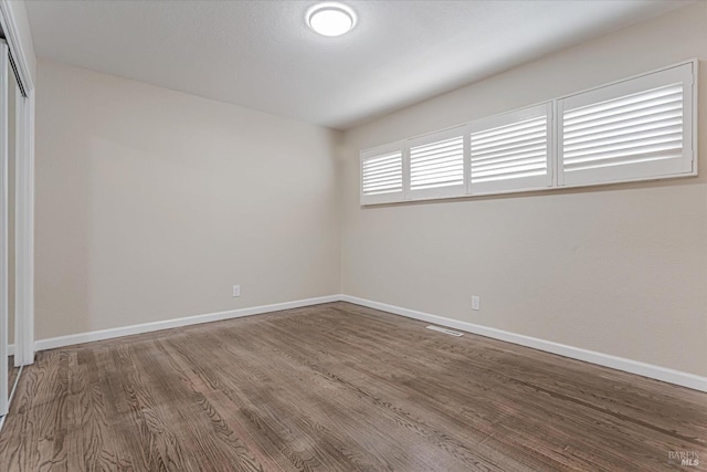 empty room featuring visible vents, baseboards, and wood finished floors