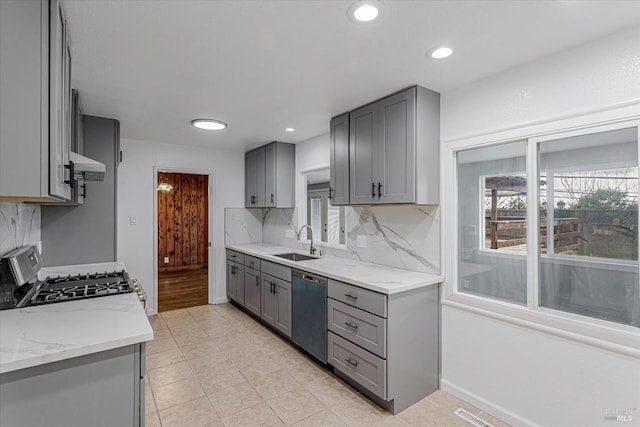 kitchen with backsplash, gray cabinets, stainless steel appliances, under cabinet range hood, and a sink