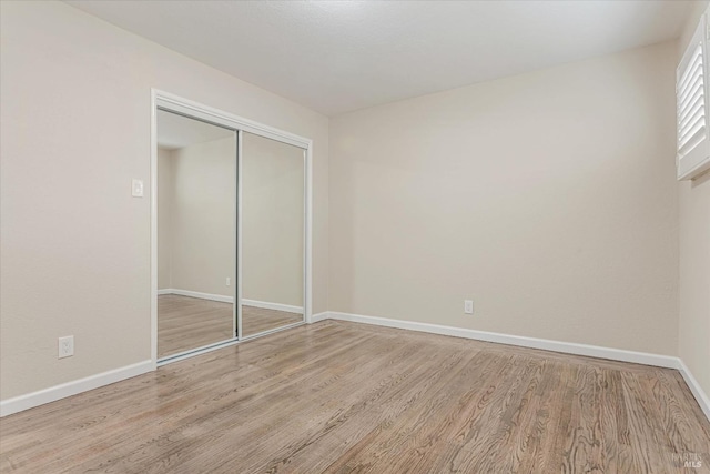 unfurnished bedroom featuring a closet, baseboards, and wood finished floors