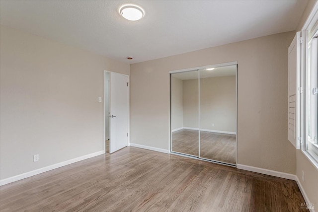 unfurnished bedroom with a closet, baseboards, and wood finished floors