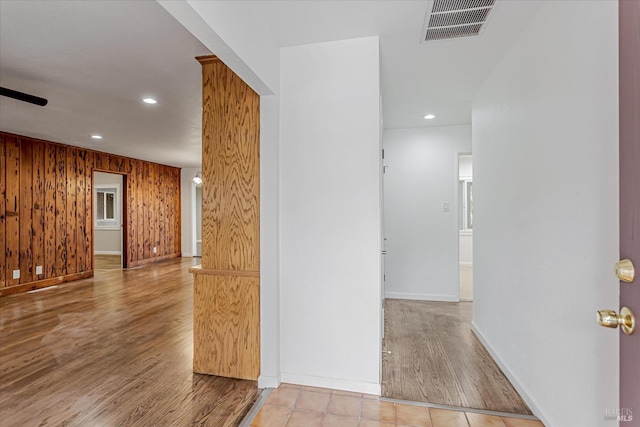 hallway with recessed lighting, visible vents, wood walls, wood finished floors, and baseboards