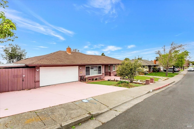 ranch-style house featuring driveway, an attached garage, a chimney, and a shingled roof