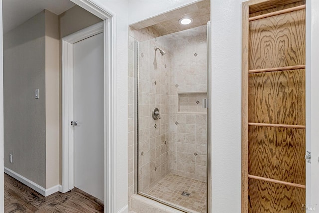 bathroom with a stall shower, baseboards, and wood finished floors