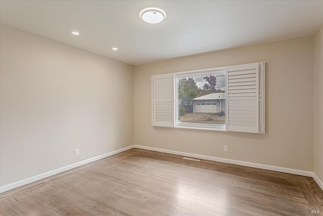 empty room featuring recessed lighting, wood finished floors, visible vents, and baseboards