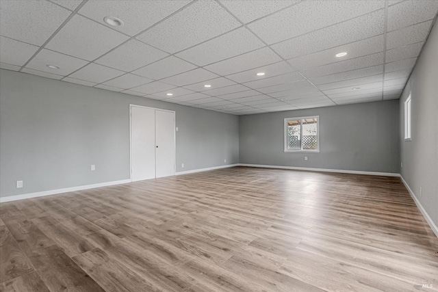 empty room with a paneled ceiling, baseboards, wood finished floors, and recessed lighting