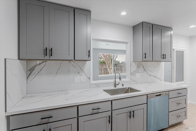 kitchen with dishwashing machine, light stone counters, gray cabinets, and a sink