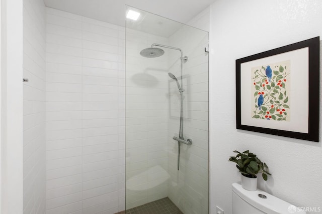 full bathroom featuring a tile shower and toilet